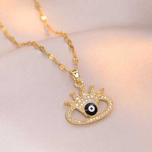 Collier couronne dorée avec pendentif œil maléfique sur un fond en soie élégant