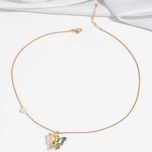 Detailed shot of golden butterfly necklace with black shell inlay and pearl accents