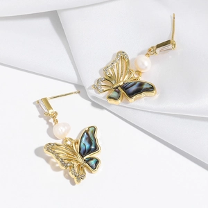 Detailed close-up of gold butterfly drop earrings with mother of pearl and pearls