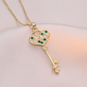 Collier clé en cœur doré avec pierre verte et zircon sur fond de satin rose délicat
