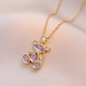 Pink teddy bear crystal pendant necklace in gold finish on soft pink silk background