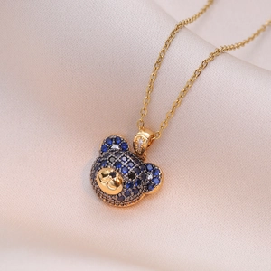 Golden bear pendant necklace with blue and black zircon stones on champagne silk