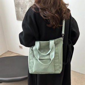 Light green waterproof nylon tote bag with front pocket and dual strap versatile design