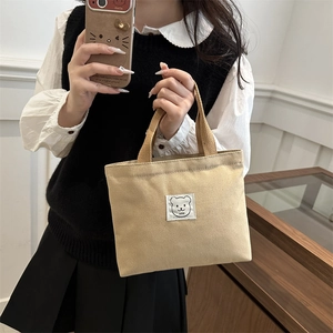 Minimalist canvas tote bag with cartoon bear patch and durable webbing handles