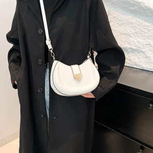 Minimalist white crescent shoulder bag with golden heart clasp on model in black coat