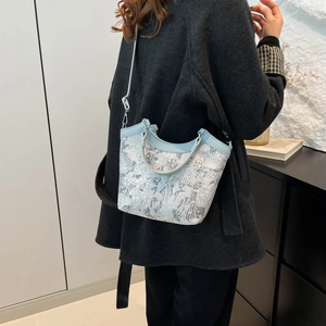 Light blue floral lace tote bag with leather straps worn by model over a dark coat