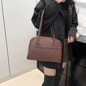 Minimalist brown large capacity tote bag with long handles shown on model in indoor setting