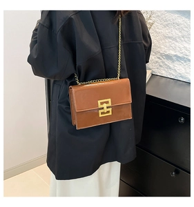 Detailed back view of a brown glossy leather shoulder bag with gold chain and square buckle