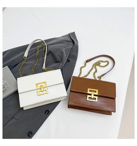 Detail of white and brown flap bags with gold hardware and chain straps on minimalist desk