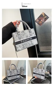 Dettaglio della borsa tote argento con ricami floreali e manici superiori chic