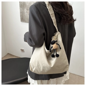 Detail of off-white nylon dumpling bag with pleated strap and sheep doll accessory