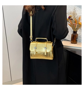 Detail of a shiny gold metallic crossbody bag with pleated texture and silver hardware
