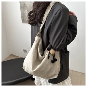 Detail of beige drawstring hobo bag with a cute black sheep plush pendant charm