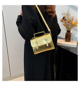 Détail du sac bandoulière doré texturé avec boucles argentées et poignée chic
