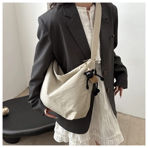 Detail of beige nylon dumpling bag with cute lamb pendant and wide shoulder strap style