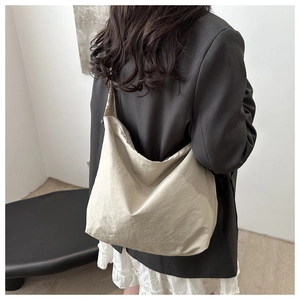 Side view of beige oversized hobo tote bag showing soft drape and nylon fabric texture
