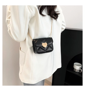 Détail du sac bandoulière matelassé noir avec fermoir cœur doré et fine chaîne dorée