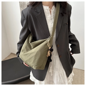 Olive green nylon hobo bag shown on model with a cute plush doll charm accessory