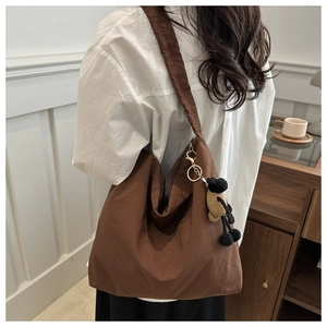 Detail of a large brown nylon hobo bag with a cute sheep plush charm on a model