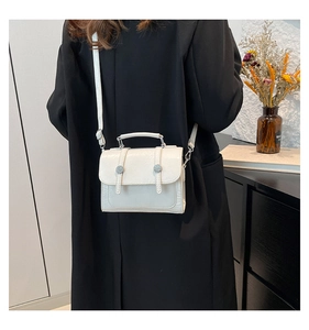 Detail of white textured mini crossbody bag with silver buckles and adjustable strap