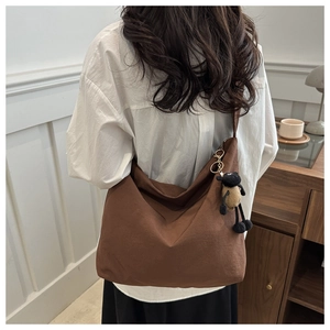 Detail of soft dark brown hobo canvas bag with a cute black sheep plush charm accessory