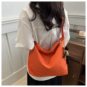 Detail of a bright orange drawstring tote bag featuring a cute plush sheep doll charm