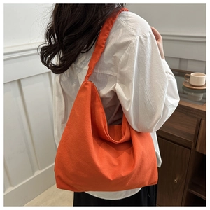 Side view of woman carrying a large bright orange nylon tote bag in a minimalist cafe