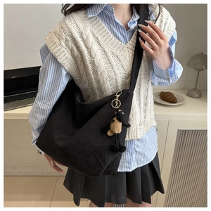 Detail of black canvas dumpling bag with cute alpaca plush charm for daily casual style