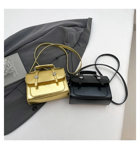 Detail of trendy glossy small square bags in gold and black with vintage buckle straps