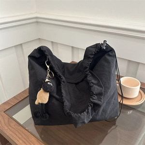 Detail of black drawstring tote bag with pleated texture and a cute sheep plush charm
