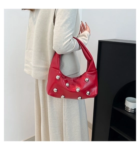Détail du sac croissant rouge orné de sphères métalliques argentées porté par un mannequin