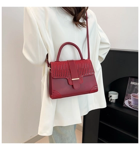 Détail du sac bandoulière bordeaux avec texture croco et boucle en métal sur modèle