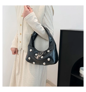 Détail du sac sous le bras noir brillant avec rivets argentés sur un mannequin