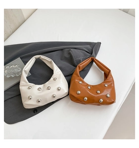 Détail de sacs croissants blancs et marrons avec finition brillante et rivets argentés