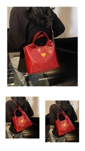 Macro detail of red glossy leather bucket bag with yellow triangle logo and handle