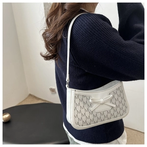Close-up of white baguette bag with bow detail and M-letter monogram print texture