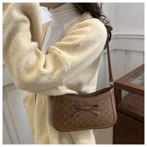 Detailed shot of retro monogram shoulder bag featuring leather bow and vintage pattern