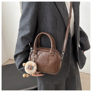 Detail der Retro-Bowlingtasche in Dunkelbraun mit Lucky-OHIO-Prägung und Löwen-Plüsch-Anhänger
