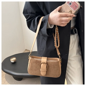 Détail du sac bandoulière en daim marron avec boucle en métal vintage et sangle tressée
