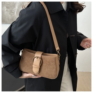 Detailed view of caramel suede shoulder bag with vintage metal buckle and leather strap
