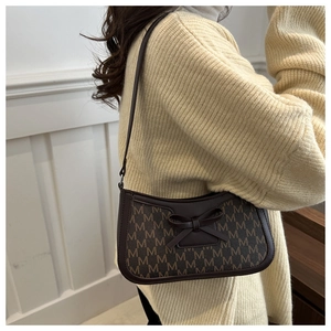 Detail of dark brown baguette bag with 'M' monogram and leather bow on knit sweater