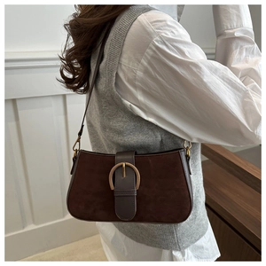 Détail d'un sac sous le bras en daim marron vintage avec boucle dorée sur un mannequin