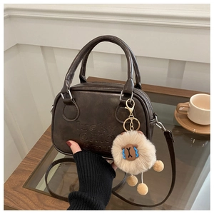 Detail der schokoladenbraunen Ledertasche mit Lucky OHIO Prägung und Plüschtier