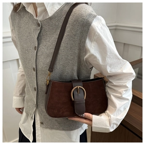 Close-up of brown retro shoulder bag featuring a gold ring buckle and mixed leather texture