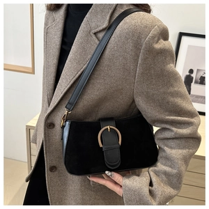 Close-up of black faux suede shoulder bag featuring a gold horseshoe metal buckle