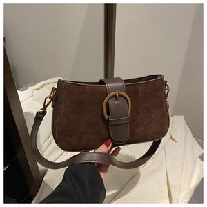 Detail of vintage coffee brown suede shoulder bag with retro round metal buckle and leather strap