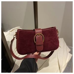 Detail of burgundy suede shoulder bag with vintage gold buckle and leather trim