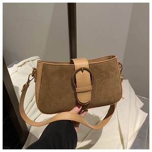 Detail view of contrast leather stitching and large round metal buckle on suede handbag