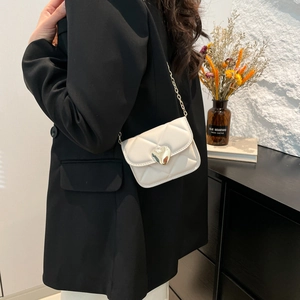 Sac à bandoulière matelassé blanc avec fermoir coeur doré et chaîne sur blazer noir