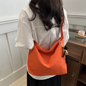 Chic orange drawstring canvas tote bag with a cute sheep plush charm on a white shirt